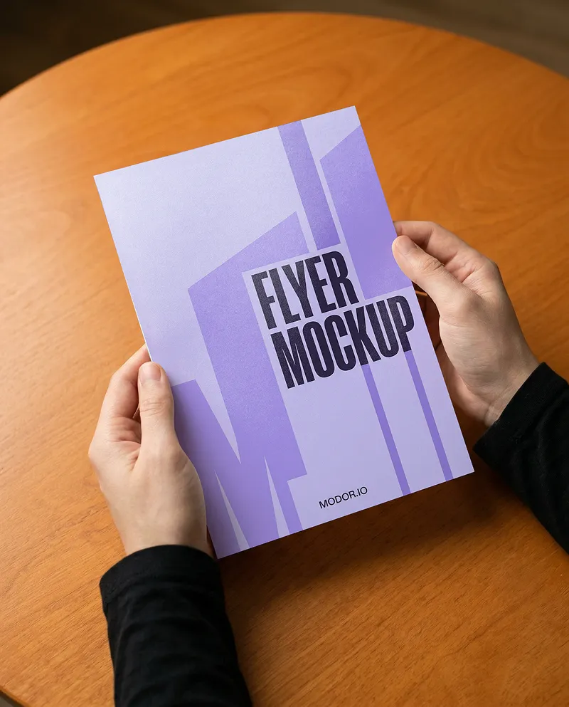 Flyer Mockup in Hands Over Wooden Table